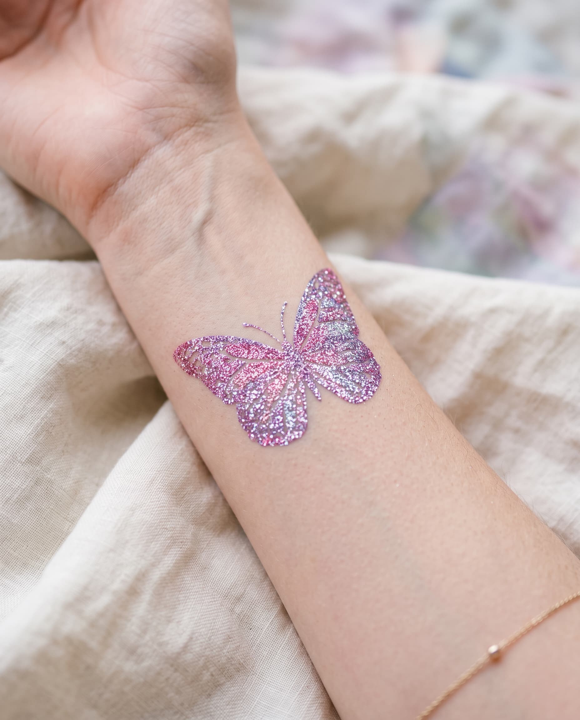 Bilek üzerinde pembe ve mor simli kelebek glitter dövme